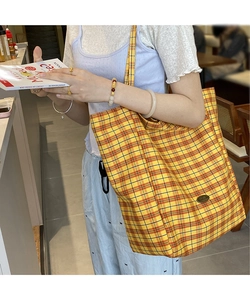 Detail shot of yellow plaid canvas tote bag showing the textured fabric and metal logo tag