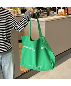 Detail of green canvas tote bag featuring white letter printing and durable shoulder strap