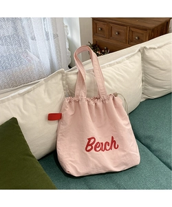 Detail of pink nylon tote bag featuring red Beach print and adjustable drawstring closure