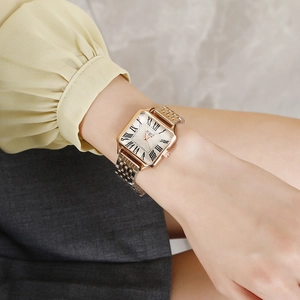 Elegant woman wearing a vintage gold square watch with roman numerals and ivory dial
