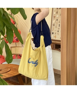 Detail of yellow waffle knit tote bag with Candy print and gray textile strap