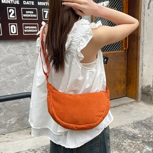 Detail of orange corduroy crescent bag showing fabric texture and adjustable strap
