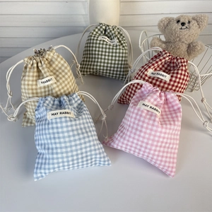 Detailed view of checkered drawstring pouches in five soft colors with cotton linen texture