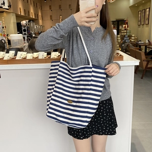 Sac fourre-tout chic en toile à rayures bleues et blanches avec étiquette cuir sur modèle