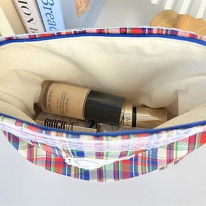 Detailed top view of a plaid canvas makeup bag with blue zipper and white lace trim
