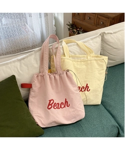 Macro detail of canvas beach tote bag with rope drawstring closure and red lettering