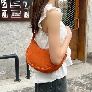 Detail of bright orange corduroy crossbody bag with textured fabric and matching zipper