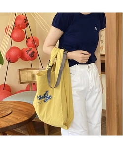 Close-up of bright yellow seersucker tote bag with blue 'Sandy' letter print for women