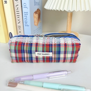 Close-up of a plaid fabric pouch with white lace trim and a metal zipper pull