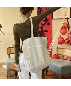 Detail of eco-friendly beige canvas tote bag with Low Classic logo and recycled label