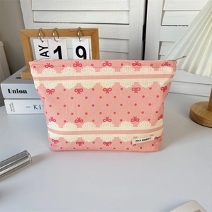 Detail of pink canvas makeup bag with lace prints, red bows, and secure top zipper closure