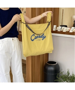 Detail of yellow waffle-textured fabric tote bag with Candy lettering and adjustable strap