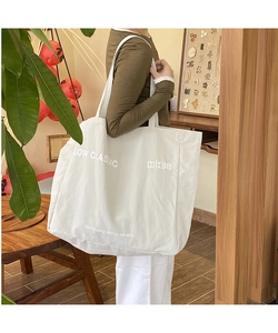 Detail of white canvas tote bag with Low Classic logo and recyclable upcycling slogan