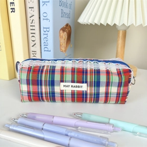Detail of red plaid cosmetic bag featuring delicate white lace trim and May Rabbit label