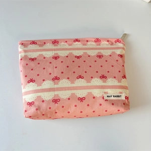 Close-up of pink canvas makeup bag with red bow prints and May Rabbit brand label