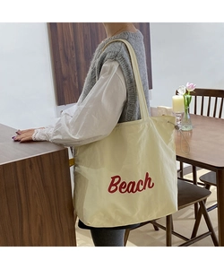 Lifestyle shot of large beige nylon Beach print tote bag with drawstring detail