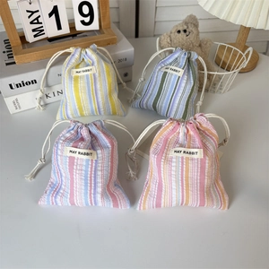Détail de quatre pochettes rayées à cordon avec étiquettes May Rabbit en décor maison