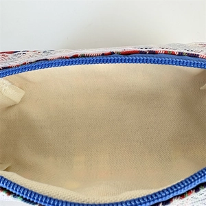 Detail of blue zipper and floral lace trim on a large capacity makeup storage bag