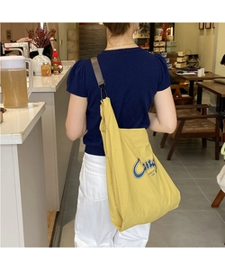 Detail of yellow nylon tote bag with blue lettering and adjustable grey shoulder strap