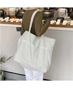 Detail of the large canvas tote bag showing the LOW CLASSIC logo and shoulder fit