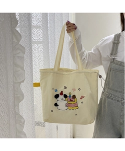 Detail of canvas tote bag with cartoon dog embroidery and yellow drawstring strap
