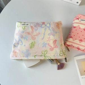 Detailed close-up of bow print makeup bag with cosmetics on minimalist background