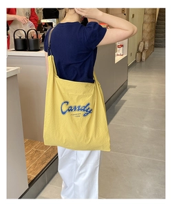 Detail of yellow waffle texture tote bag with blue Candy print worn by model
