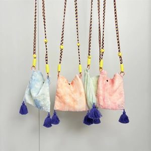 Detail view of multi-color tie-dye mini crossbody bags with woven ropes and tassels