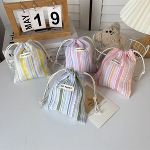 Détail de quatre pochettes rayées à cordon avec étiquettes May Rabbit en décor cosy