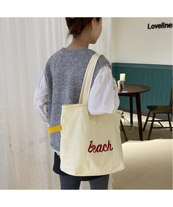 Detail of Beach print nylon tote bag with red embroidery and yellow strap on shoulder