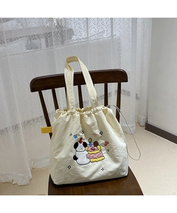 Close-up of drawstring tote bag with panda embroidery on wooden chair and lace background