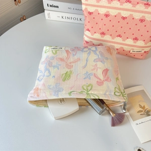 Close-up of floral bow canvas makeup bags with metal zippers and woven brand labels