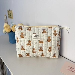 Détail de la trousse de maquillage matelassée avec ours et ruban blanc sur le zip