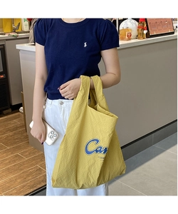 Detail of vibrant yellow textured fabric tote bag with blue Care lettering detail