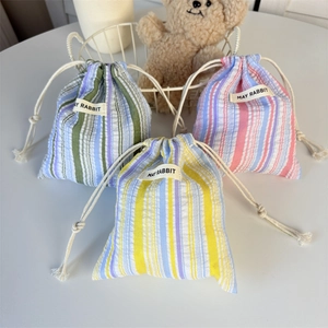 Trois pochettes à cordon rayées avec étiquettes May Rabbit dans un décor doux