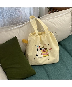 Detail of cute cartoon puppy embroidery on a light yellow drawstring canvas tote bag