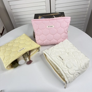 Detailed view of quilted flower makeup bags in pink, yellow, and white with floral patterns