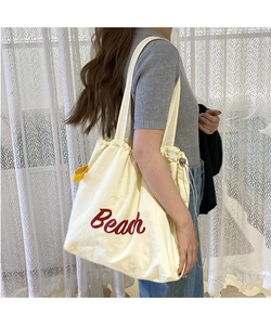 Detail view of nylon drawstring tote bag with red Beach embroidery and side handle