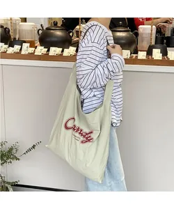 Close-up of green checkered nylon tote bag with Candy print and wide shoulder strap