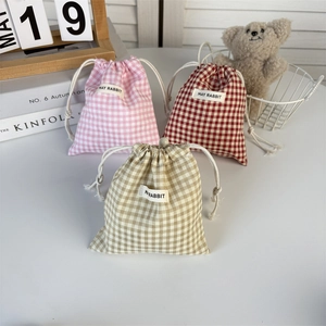 Three plaid drawstring storage pouches in pink, red, and brown cotton fabric