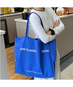 Macro detail of royal blue tote bag with white minimalist branding and wide shoulder strap