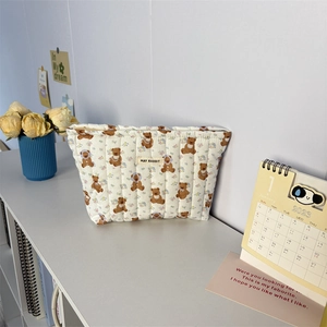 Détail de la trousse de toilette en coton matelassé avec motif d'ours et étiquette