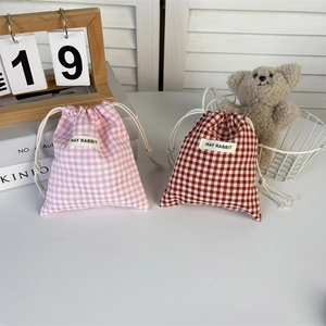 Detail of plaid cotton drawstring storage bags in pink and red with May Rabbit label