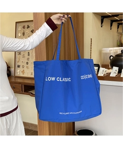 Detail of blue canvas tote bag featuring white LOW CLASSIC logo and durable shoulder strap