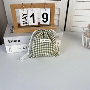 Detail of green gingham drawstring bag showing cotton texture and May Rabbit label