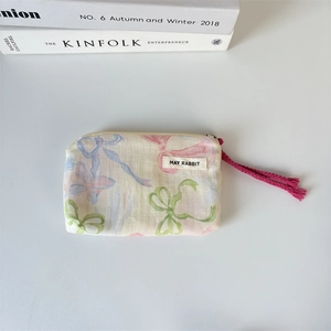 Detailed shot of floral bow canvas makeup bag with pink tassel zipper and brand label