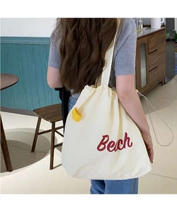 Close-up of cream nylon tote bag with red Beach print and side drawstring detail