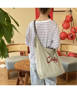 Detail of light green nylon tote bag with red Cady print and adjustable strap