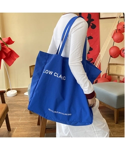Close-up of a large navy blue canvas tote bag with bold Low Claic white lettering