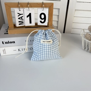 Detail of blue and white checkered drawstring bag with May Rabbit label and cotton rope